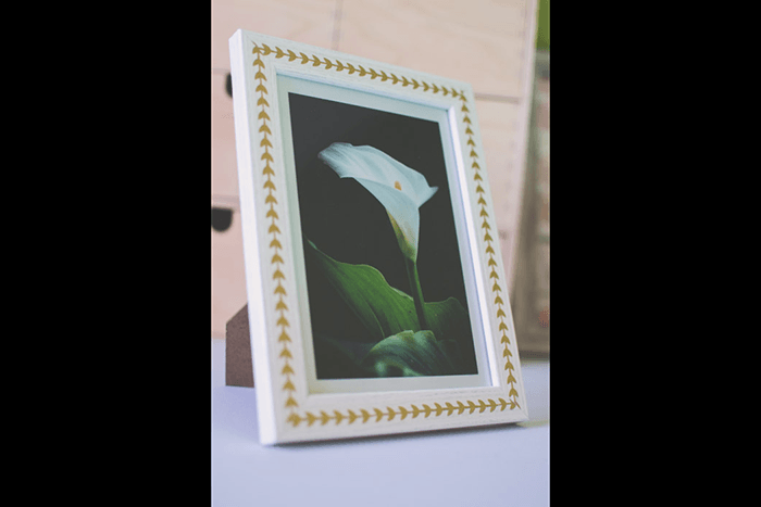 A reused white frame with patterned washi tape around its border as an idea for what to do with photos