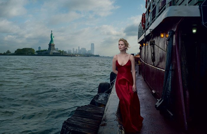 Annie Leibovitz portrait of a girl in a red evening dress standing on a dock with sea and empire state building behind her