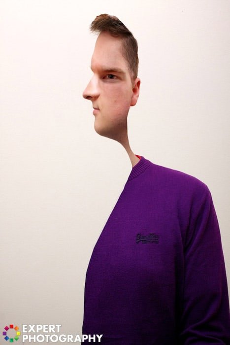 A man in purple jumper, with a creative cut out effect on his face which makes him look like a subject in a Picasso painting 