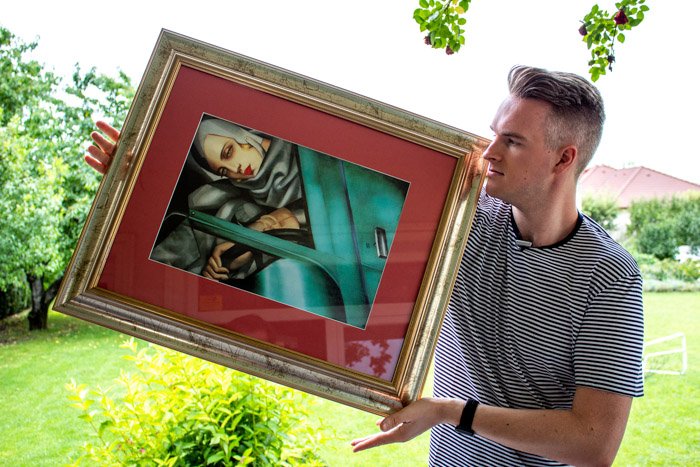 A man holding a framed painting outdoors