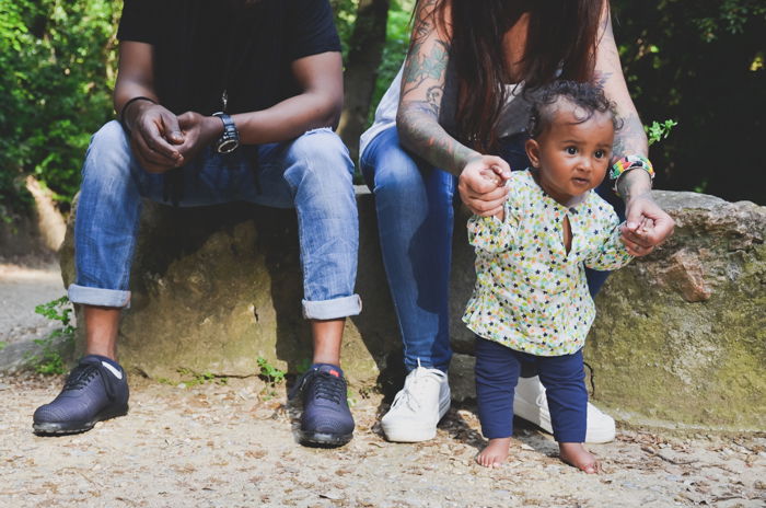 Close up family photo of a woman holding a small baby s hands with a man beside her