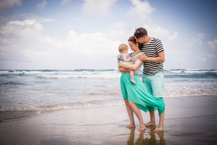 Lifestyle shot of a couple with a small baby standing on the beach - composition for family portraits