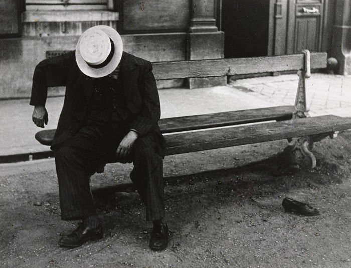 Man in hat sleeping while sitting on a bench