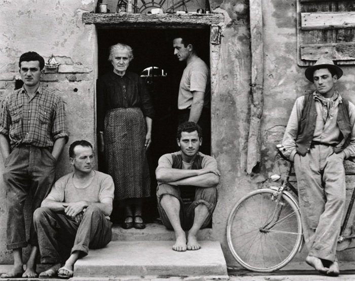 Black and white image of poor family gathered by the door