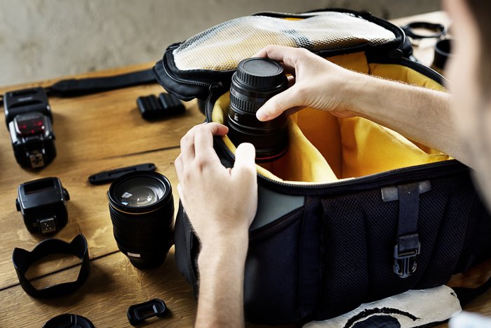 A person organising their travel photography camera bag
