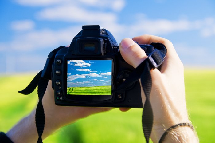 Close up of a person checking their DSLR camera settings for landscape photography