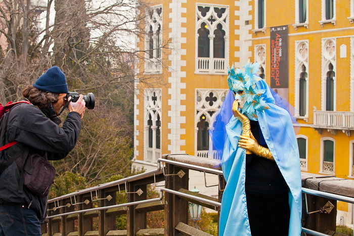 A man taking a photo of a person in an extravagant carnival costume during a travel photography trip