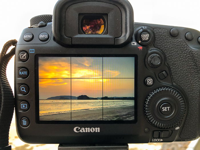 A canon DSLR with a beautiful sunset seascape onscreen