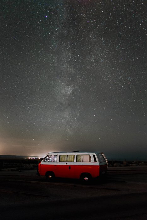 Image of a red camper van parked under an impressive starry sky after using focus stacking to help remove star trails