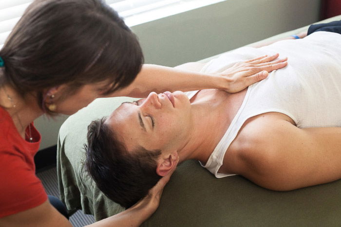 A business portrait of a woman giving a massage to a man lying on a table 