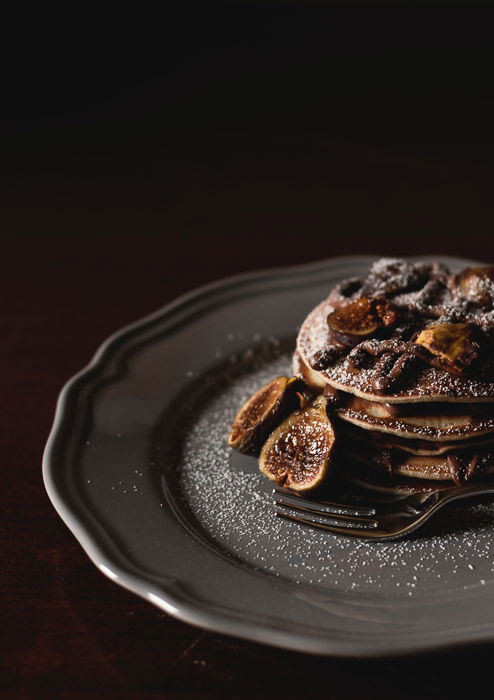 A dark photography still life setup of a luxurious dessert on a plate against a dark background