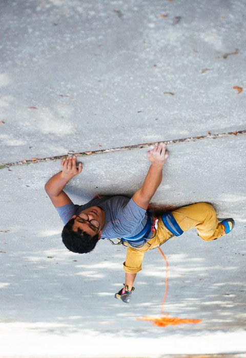 A fun photo of a man in climbing gear on a footpath giving the illusion he is rockclimbing