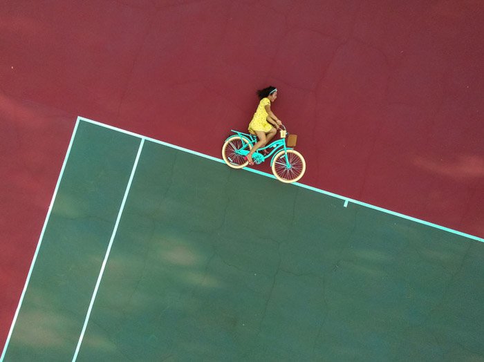 Optical illusion photo of a girl on a bike which looks like she is cycling on abstract lines