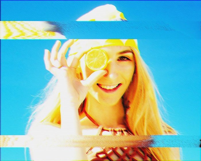 Analog glitch art image of a girl holding a lemon to her head