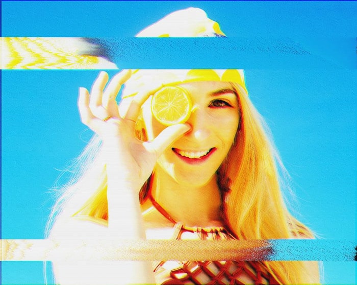 Analog glitch art image of a girl holding a lemon to her head