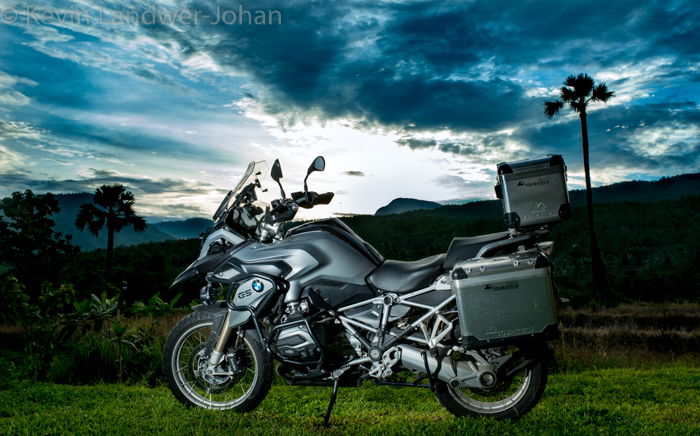 A silver motorbike with a stunning landscape behind and a watermark on top created in lightroom.