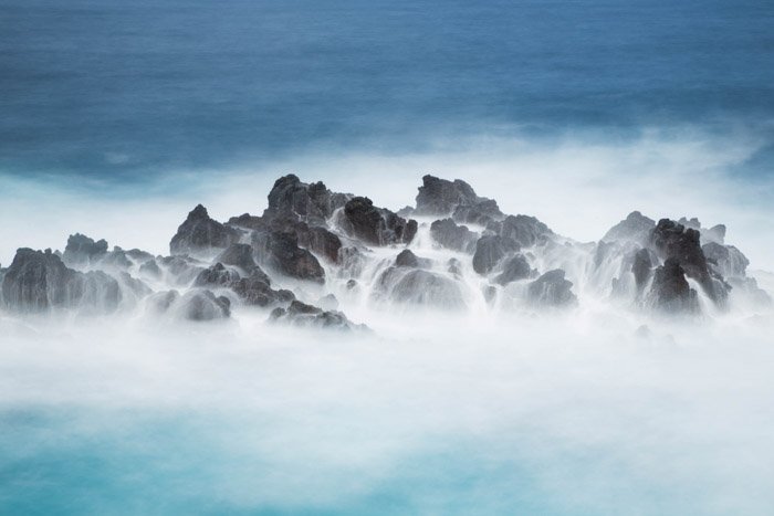 通过长期曝光捕获的海洋中的岩石上的雾气