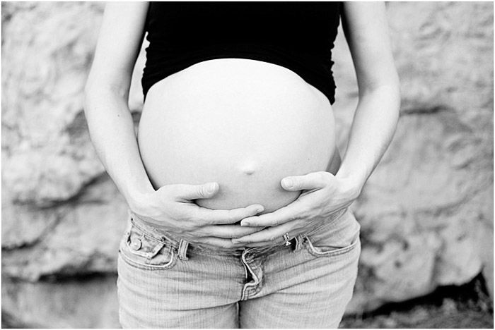 Black and white portrait of a pregnant woman holding her belly