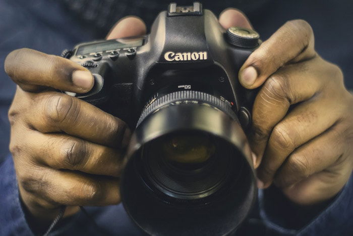 Close up of a man holding a Canon full frame DSLR fitted with a 50mm nifty fifty