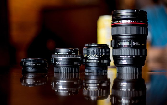 four different types of photography lenses on a table with reflections