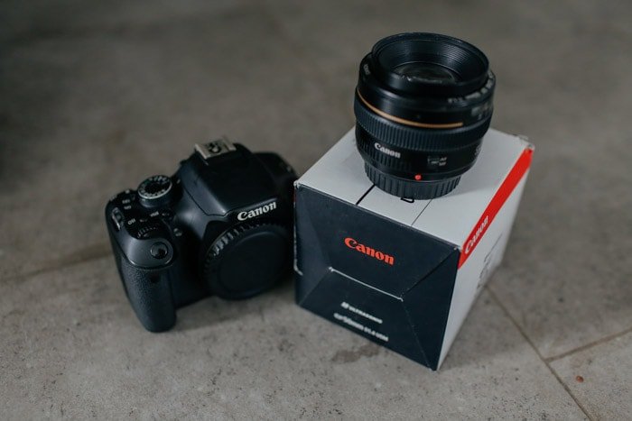 A canon camera with the 50mm nifty fifty prime lens on top of its packaging box