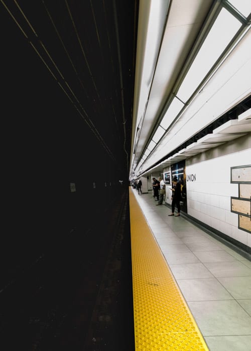 The dark metro tunnel on one half, and the people waiting on the bright platform