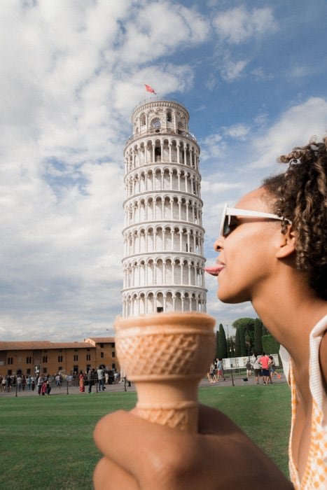 Fun forced perspective photography shot of a girl posed to make it appear she is licking the leaning tower of Pisa in an ice cream cone