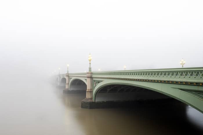 Atmospheric shot of a green bridge disappearing into fog 