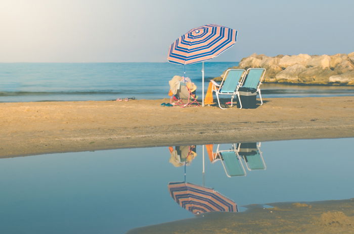 Serene beach photo of deckchairs and umbrella with the sea in the background