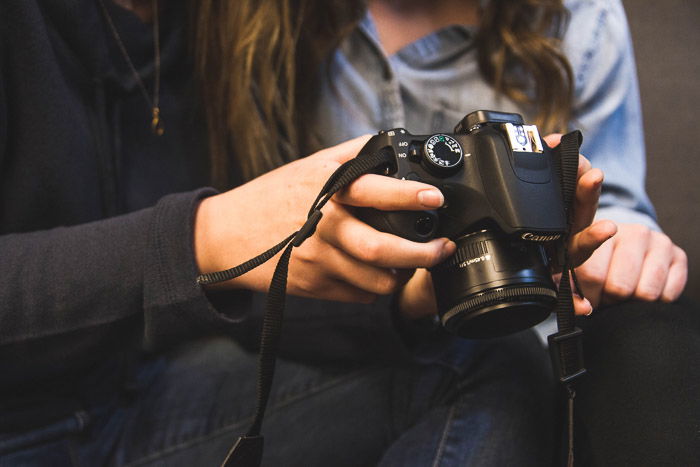 Close up shot of girls holding a DSLR and looking at the screen - why you need photography insurance and camera insurance