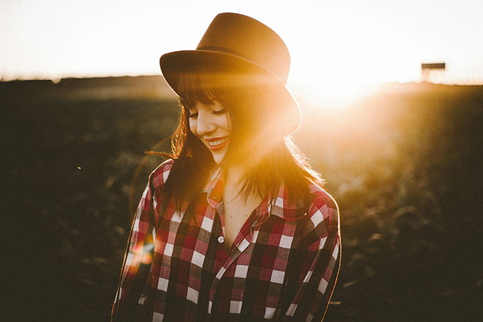 Portrait of a female model wearing a hat with the bright glare of the sun behind her serving as an interesting portrait background