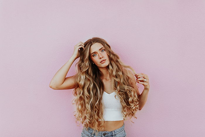 Portrait of a blonde girl posing in front of a pink portrait background