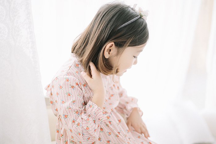 Portrait of a little girl sitting in front of a soft white backdrop 