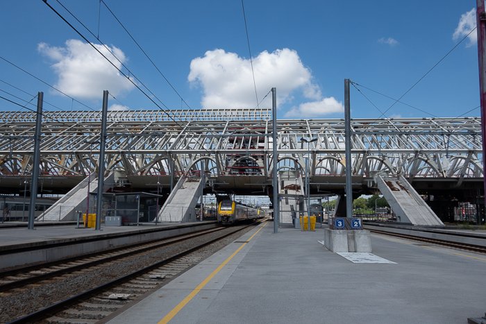 Photo of a train pulling into a railway station on a day with blue skies and clouds