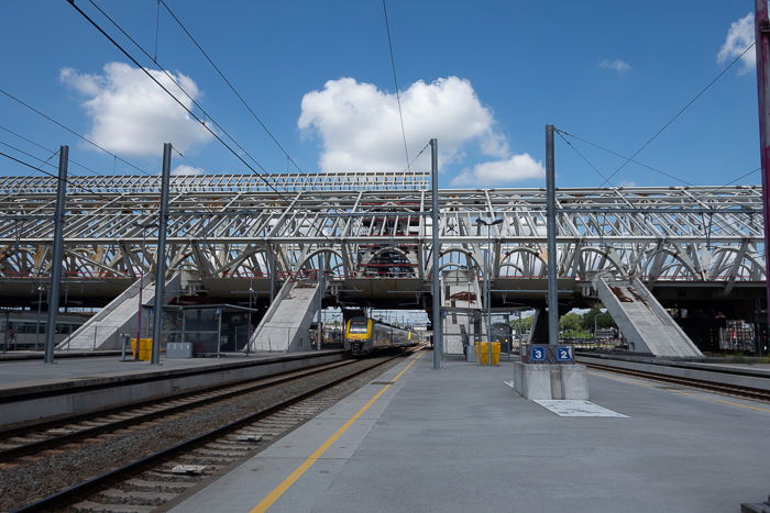 Photo of a train pulling into a railway station on a day with blue skies and clouds