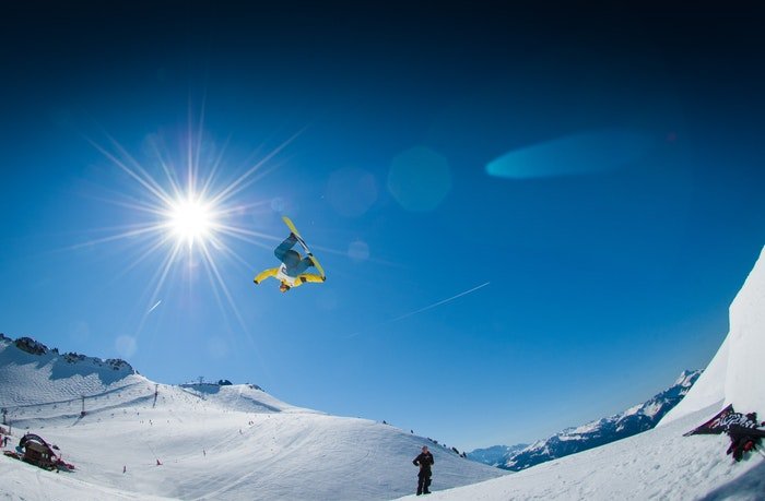 Snowboarder int the air above snowy mountains 