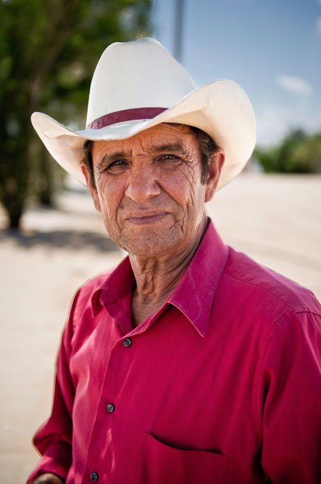 A travel photo of a man in a cowboy hat and pink shirt - tipping for photos of people
