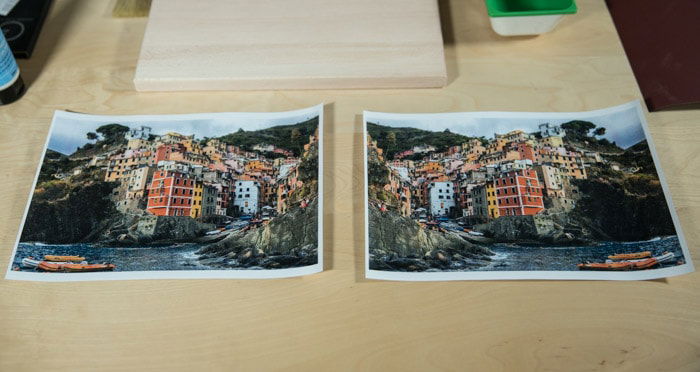 Two identical photos of a brightly colored coastal town, resting on a wooden board preparing to transfer photo to wood