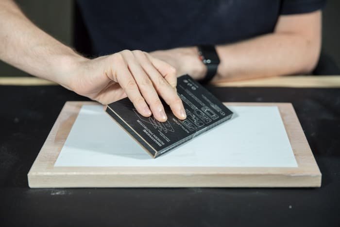 A man preparing a wooden board to transfer laser print to wood