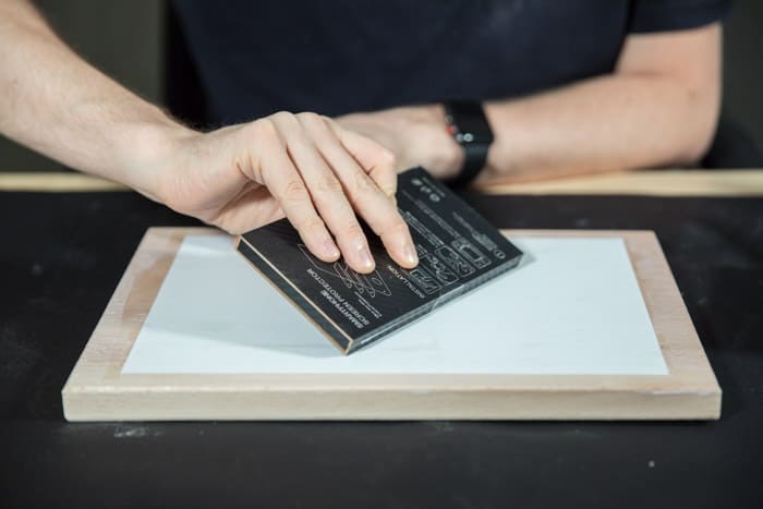 A man preparing a wooden board to transfer laser print to wood