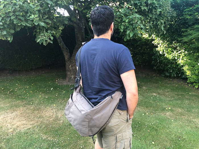 Photo of a man carrying a sling camera bag 