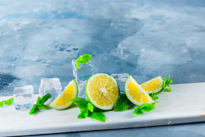 Set up for water splash photography with acrylic ice cubes, limes on blue background