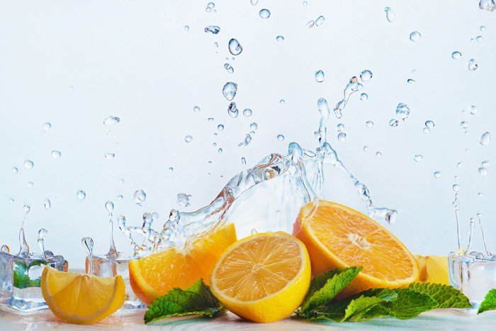 a creative food photography set up with oranges and water splashes on white background