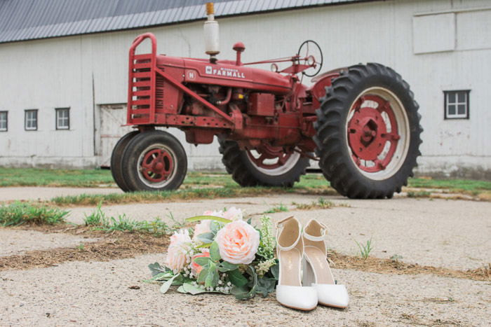 Humorous wedding photography still life of wedding accessories on the ground in front of a red tractor