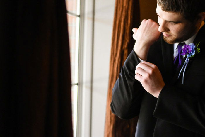 Portrait of a groom buttoning his shirt sleeves -best tripod for wedding photography gear