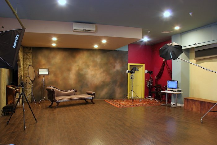 A photography studio setup with lighting, tripod, and laptop