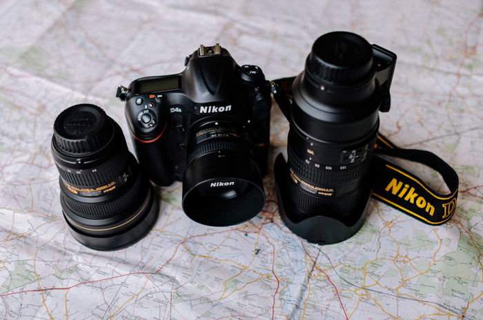 A Nikon dslr camera and two different wide angle lenses resting on a map