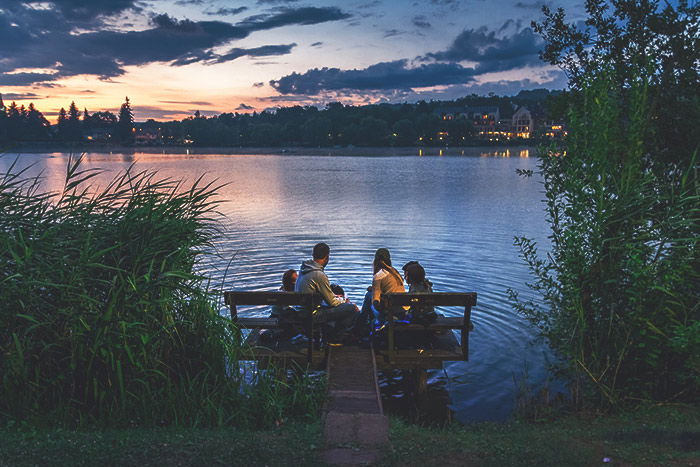 Photo of a family sitting beside a lake at sunset