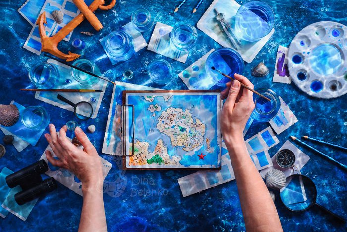 Flat lay photography idea: hands painting a small map underwater