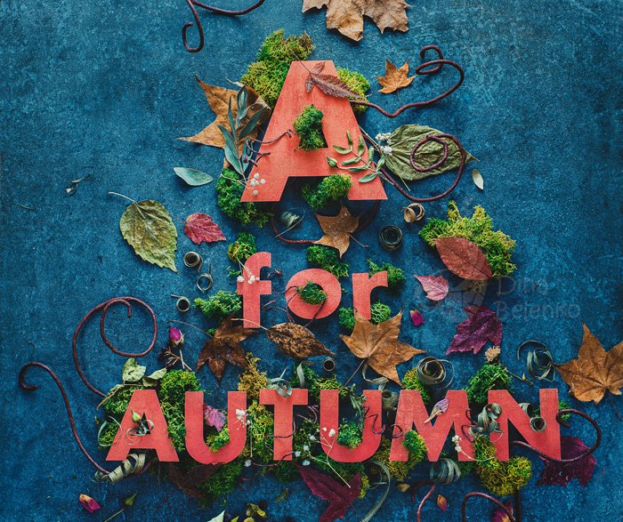 Cute autumn flat lay photo inspiration: cut out text 'A for autumn' on a blue surface